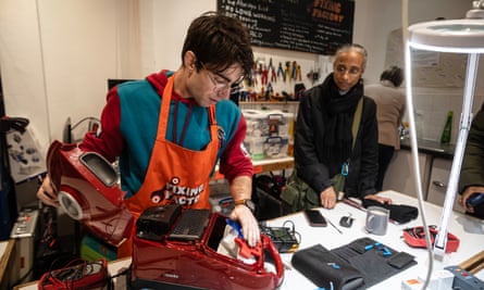 A worker repairs a vacuum cleaner at a repair shop.