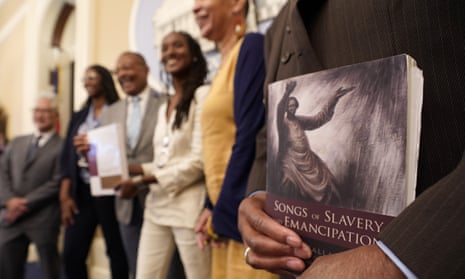 Amos Brown, the vice-chair for the California taskforce, right holds a copy of the book Songs of Slavery and Emancipation, at an event in Sacramento in June.