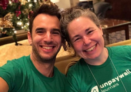 A man and a woman smiling and wearing green shirts.