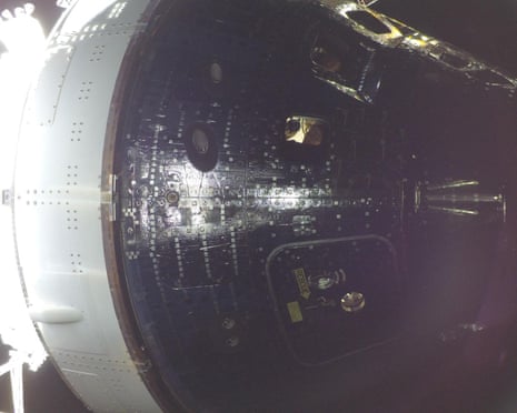 क्रिस्टीना कोच और शून्य गुरुत्वाकर्षण संकेतक को ओरियन अंतरिक्ष यान की एक खिड़की के माध्यम से देखा जाता है।