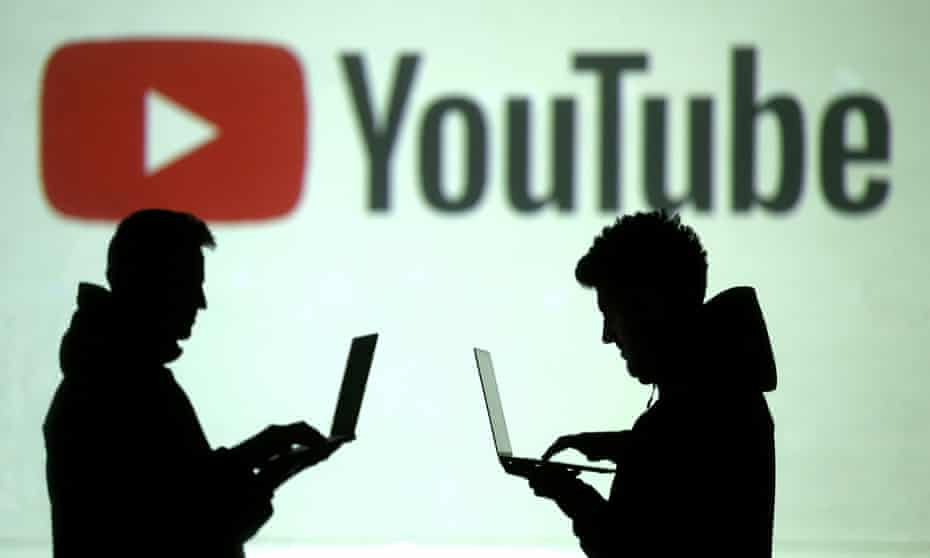 Silhouettes  of laptop users in front of YouTube logo