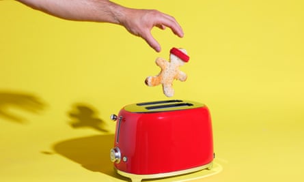 A toaster with a gingerbread man-type figure popping out of it and a hand catching it