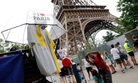 A person takes a photo of merchandise on a stall besides the Eiffel Tower