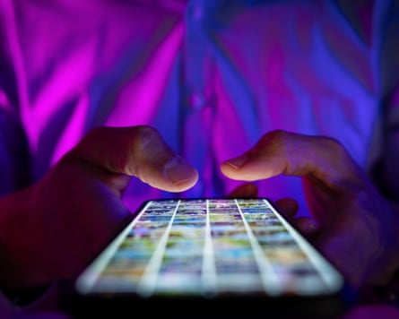 man scrolling mobile phone screen in dark room with neon lights. internet browsing, social media and marketing