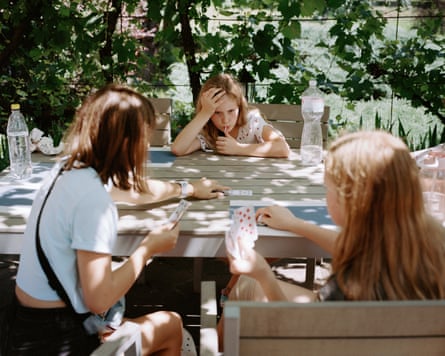 Kids play a cardgame around a table outdoors