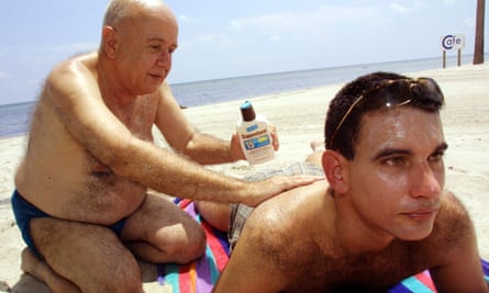 man puts sunscreen on another man's back