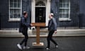 Two men carry Sunak's lectern in Downing Street.