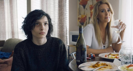 Wolfhard and Paulson sit at a table with plates of half-eaten food and a bottle of wine