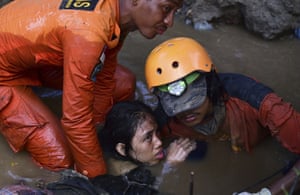 Rescuers evacuate an earthquake survivor by a damaged house.