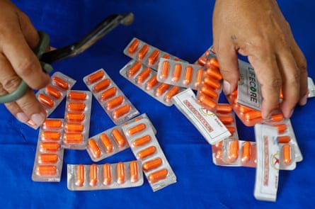 A person cuts packaged drug capsules