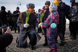 A honour guard kneels as he gives a flower to a girl on International Women’s Day