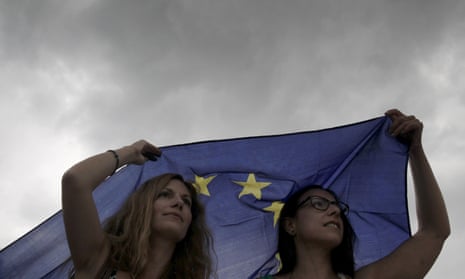 Greek protesters sheltering from rain under an European Union flag