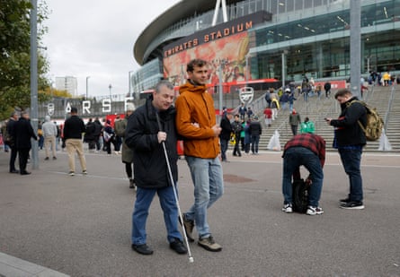 Daniel Bailey, a blind Arsenal supporter, is helped on his way into the ground before a match