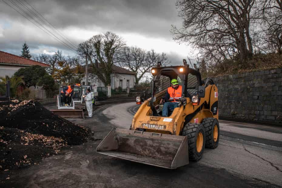 Workers near the village of Zafferana Etnea clean volcanic sand from the main streets