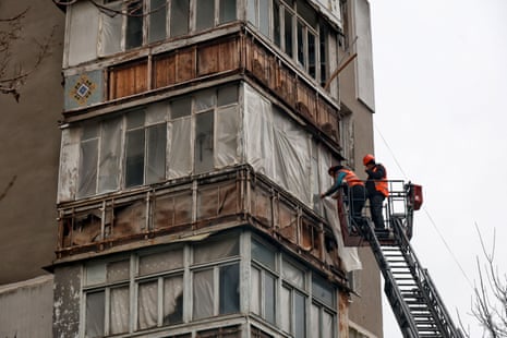 Men in a crane inspect the side of an aprtment building