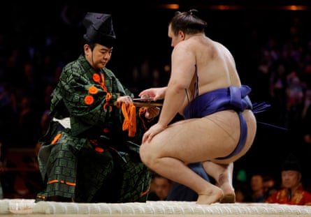 Aonishiki, the 21-year-old Ukrainian who fled from his war-torn country, picks up his prize money from the referee’s fan. The envelope contains a 10,000 yen banknote (approx £50)