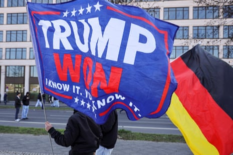 A far-right activist carries a large "Trump Won" flag beside a German national flag