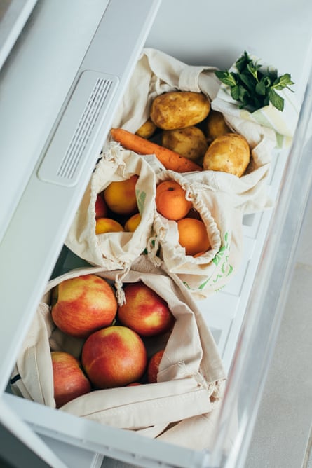 vegetables and fruit in reusable cotton bags inside of a refrigerator