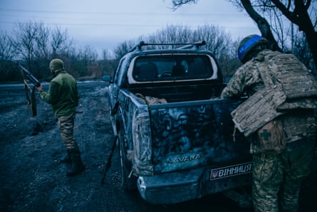 Pavuk, with his back to the camera, reaches into the back of a pick-up truck