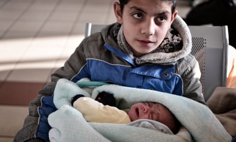 A refugee boy holds his baby brother at the port of Piraeus, Greece, in February 2016.