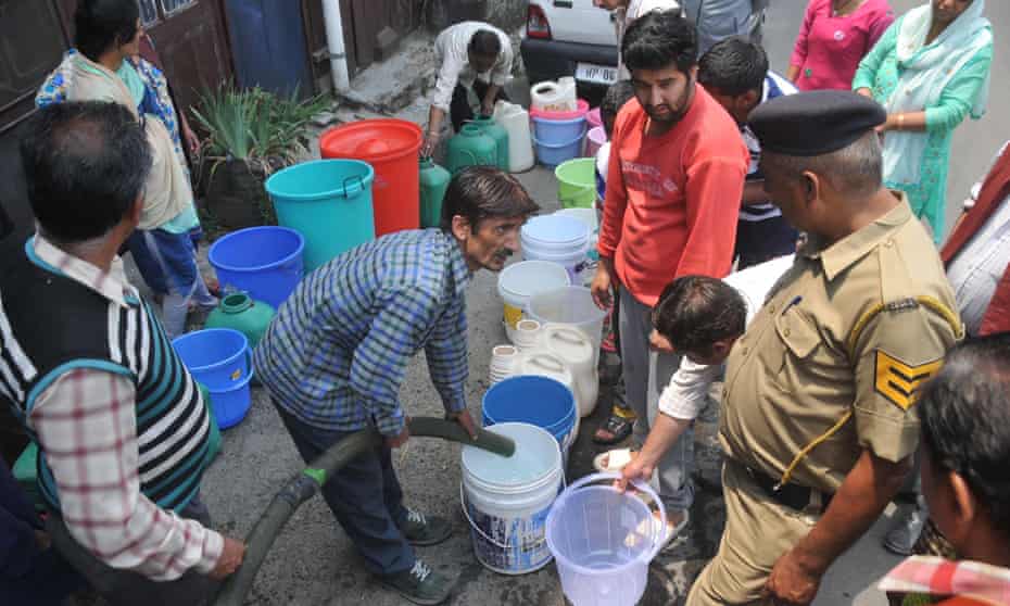 Locals gather to collect drinking water in buckets from a truck. 