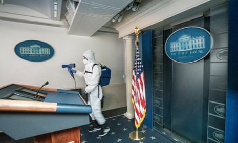 A cleaner at the White House sprays disinfectant in the James Brady Press Briefing room after US President Donald J. Trump return to the White House