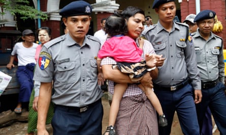 Kyaw Soe Oo, escorted by police, holds his daughter as he leaves the court during a break on 18 June