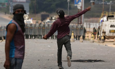 A man throws stones at Venezuelan national guards troops, at the Brazilian border on Sunday.
