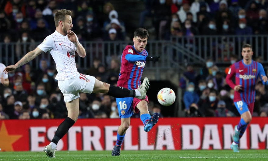 Pedri, playing for Barcelona, puts the ball past Ivan Rakitic of Sevilla during a league encounter in April