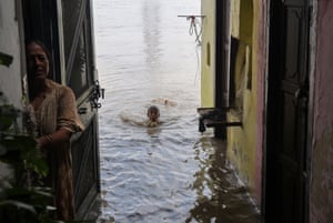 A child swims towards a flooded a doorway where a woman is standing
