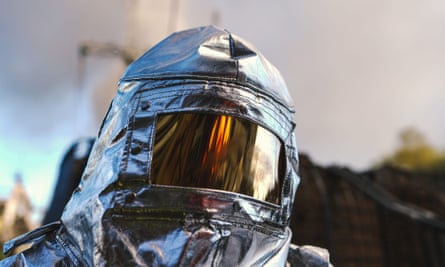 Jefe de bomberos con traje plateado con visera que refleja el fuego