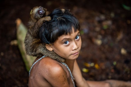 Indigenous boy in the Amazon, looking up to camera, with a monkey round his neck.