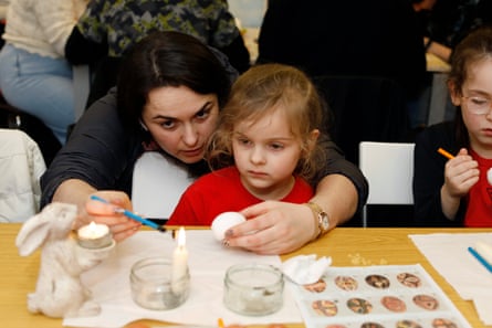 Tamara shows her daughter how to draw on an egg with wax