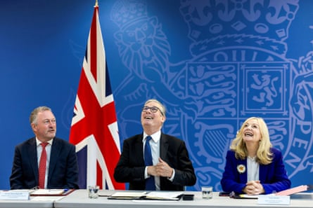 Keir Starmer looks up, flanked by Steve Reed and Tracy Brabin