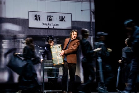 Protagonist Watashi is struggling with his case as he moves through a crowd at a Tokyo staton