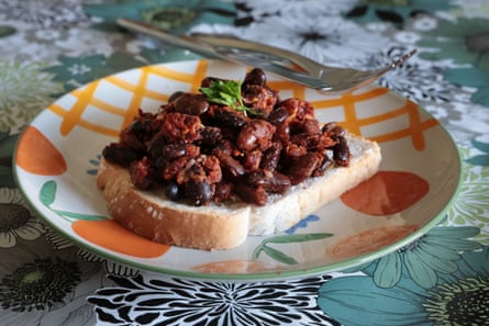 A plate of beans in a sauce on a slice of bread
