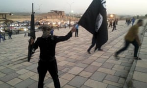 A fighter holds an Islamic State flag and a weapon on a street in the city of Mosul, Iraq. US defense secretary Ashton Carter has promised assaults on the city in 2016.