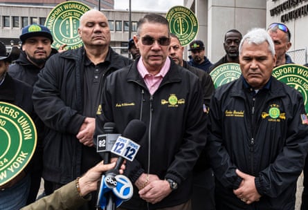 a man speaks into a microphone while surrounded by people