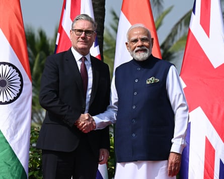 Keir Starmer and Narendra Modi shake hands in front of flags.