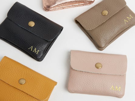 A selection of small leather purses in ochre, pale pink, black and dark beige on a white background