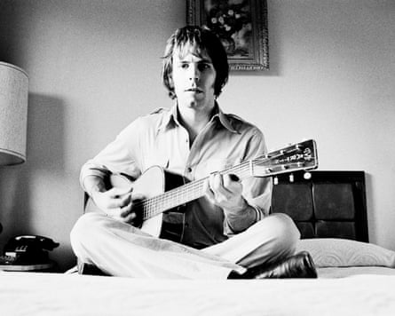 Bob Weir playing guitar on a bed in a black and white image.