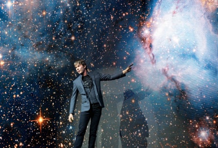 Brian Cox in front of a mural of stars and galaxies