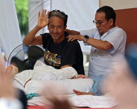 Sonam Wangchuk waves to a crowd while receiving a back massage