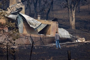 A man standing by a burnt out house.