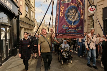 Ebla Mari and Dave Turner march with miners’ banners in a scene from Ken Loach’s 2023 film The Old Oak