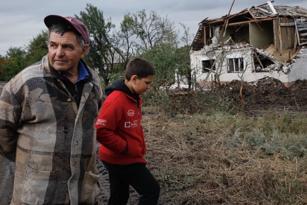 A grandfather and grandson stand next to their neighbours’ house, which was destroyed by a bomb on 6 September.