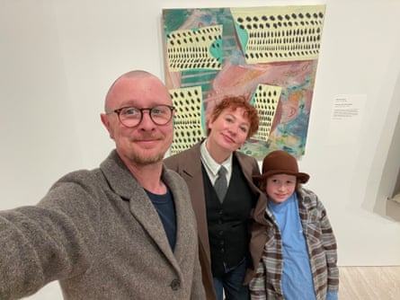 A father, mother and son in front of an artwork in a gallery