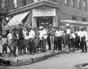 A crowd of men and armed National Guard stand in front of the Ogden Cafe during race riots in Chicago.