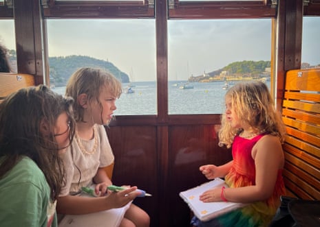 Photograph of three young girls arguing on a tram with the sea in the background