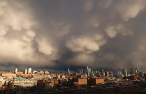 Storm clouds pass over the lower Manhattan skyline as a rainstorm moves through New York City at sunset